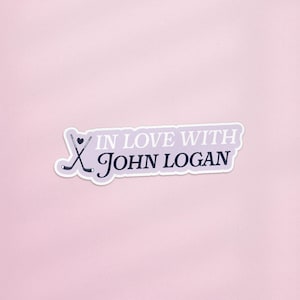 May include: A sticker with the text "IN LOVE WITH John Logan" in a stylized font. The sticker features a hockey stick graphic and a heart. The background is a light purple color.