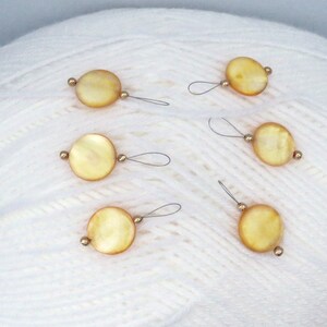 May include: Six yellow and white round yarn needle threaders with gold beads.