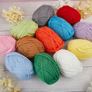 Op de afbeelding: Assortiment van kleurrijke garenbollen in verschillende tinten blauw, groen, geel, oranje, roze, rood, bruin en grijs. Het garen is gemaakt van zacht, dik materiaal en is perfect voor knutselprojecten.