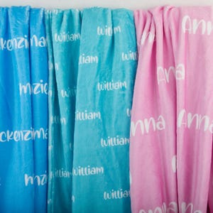 May include: Three fleece blankets with personalized names printed on them. The blankets are blue, turquoise, and pink.