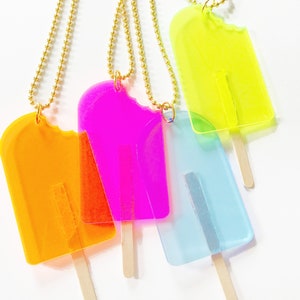 Kids translucent popsicle necklaces in fun bright colors including pink, orange, blue and neon yellow with real popsicle sticks, 24" long gold ball chain. As seen in Buzzfeed