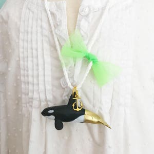Orca also known as Killer whale with gold tail on nautical cording with gold anchor charm and lime green tulle bow. CPSIA safety clasp. 24 inches long.