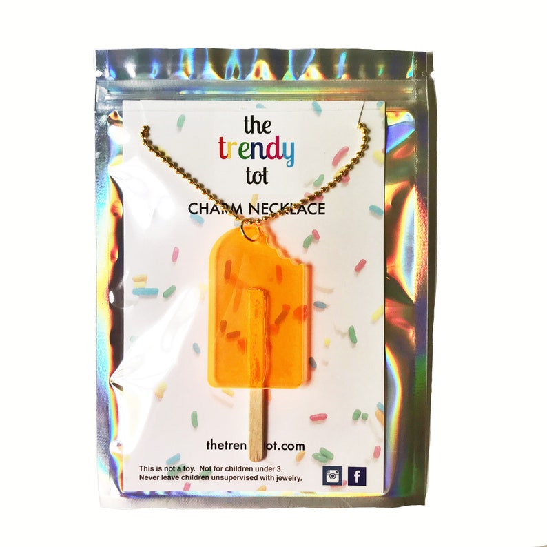 Orange translucent popsicle with bite and real wooden popsicle stick in creative iridescent freeze-dried ice cream packaging. 24 inches long. Great for kids or adults.