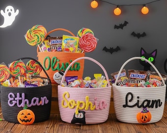 May include: Three Halloween-themed rope baskets filled with candy and lollipops. Each basket is personalized with a name: Ethan, Olivia, Sophia, and Liam. Decorations include a jack-o'-lantern, ghost, and bats.