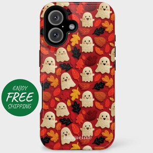 May include: A red phone case featuring a pattern of smiling ghost figures and autumn leaves in shades of orange, yellow, and brown. The case has a black camera module and the name "Jacqueline" is printed at the bottom.
