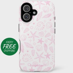 May include: A white phone case with a pink seashell and starfish pattern. The case has a cutout for the camera lens and a black border. The text "Jacqueline" is printed on the bottom of the case.