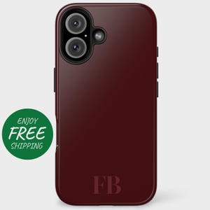May include: Burgundy phone case with a black camera lens and the initials "FB" printed in a burgundy color.