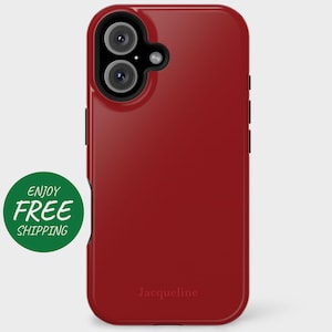 May include: Red phone case with a black camera cutout and the word "Jacqueline" printed on the bottom.