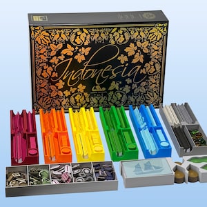 Può includere: Gioco da tavolo "Indonesia Third Edition" con una scatola nera con disegni floreali dorati e scritte. Il gioco include pezzi di vari colori: rosso, arancione, giallo, verde e blu, riposti in diversi contenitori.