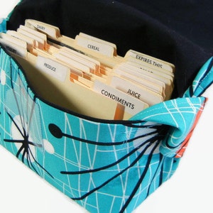 May include: A turquoise and white fabric bag with a black and white geometric pattern. The bag is open and filled with labeled file folders. The labels include "Dairy", "Cereal", "Produce", "Condiments", "Juice", and "Expires This".