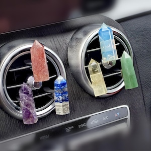 Può includere: Sette punte di cristallo di diversi colori sono visualizzate in una bocchetta di ventilazione di un'auto. I cristalli sono di colore ametista, quarzo rosa, lapislazzuli, quarzo chiaro, citrino, aventurina verde e selenite.