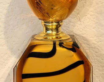 Frasco de perfume de vidrio artístico con diseño en espiral ámbar y negro, base rectangular con tapa ovalada, 15 cm de altura.