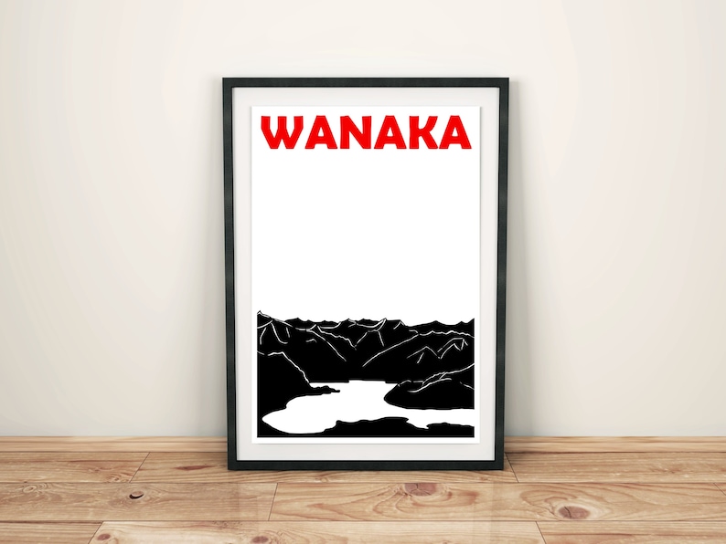 Puede incluir: Impresi&oacute;n art&iacute;stica enmarcada con la palabra "WANAKA" en rojo sobre una ilustraci&oacute;n en blanco y negro de una cordillera y un lago. La impresi&oacute;n est&aacute; en un marco negro, apoyada contra una pared blanca sobre un suelo de madera. Dise&ntilde;o de paisaje.