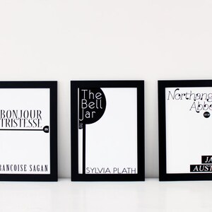 Peut inclure: Trois impressions encadr&eacute;es noires avec du texte blanc sur un fond blanc. L'impression de gauche indique "Bonjour Tristesse" de Fran&ccedil;oise Sagan. L'impression du milieu indique "The Bell Jar" de Sylvia Plath. L'impression de droite indique "Northanger Abbey" de Jane Austen.