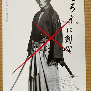 Puede incluir: Un cartel en blanco y negro de la película "Rurouni Kenshin" con una persona vestida con ropa tradicional japonesa sosteniendo una espada. El cartel incluye texto en japonés y una gran "X" roja. El texto "8.25 ROADSHOW" está en la parte inferior.