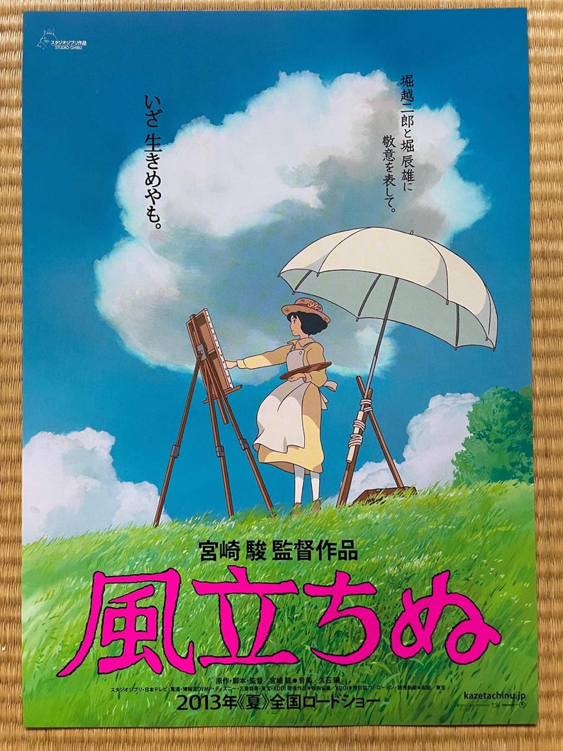 May include: A movie poster featuring a woman painting on an easel under a white umbrella. The poster has Japanese text and a title in pink. The background shows a blue sky and green grass. The poster is for a 2013 film.