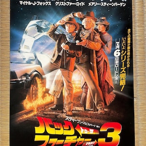 以下が含まれることがあります： 映画「バック・トゥ・ザ・フューチャー PART3」のポスター。マイケル・J・フォックス、クリストファー・ロイド、メアリー・スティーンバージェンが出演。ポスター上部には日本語のテキストがあり、映画タイトルは様式化されたフォントで表示。デロリアンは炎とともに描かれています。