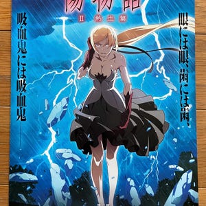 May include: Poster for the anime film "Kizumonogatari II: Nekketsu-hen." The image features a female anime character in a dark dress against a backdrop of lightning and a blue sky. Japanese text is visible.
