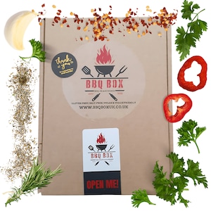 Peut inclure: Une boîte en carton marron avec un autocollant blanc qui dit "BBQ BOX" et qui représente une flamme rouge et un barbecue. L'autocollant indique également "Unique BBQ Seasonings 2021" et "Gluten-Free | Salt-Free | Vegan & Veggie Friendly" et "www.bbqboxuk.co.uk". Il y a un plus petit autocollant blanc sur la boîte qui dit "BBQ BOX" et qui représente une flamme rouge et un barbecue. Le plus petit autocollant indique également "Open Me!"
