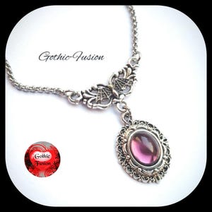 May include: A silver necklace with a purple gemstone pendant. The pendant is surrounded by intricate silver filigree. The necklace has a delicate chain and a butterfly-shaped charm.