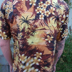 May include: A brown and yellow short-sleeved shirt with a tropical print featuring palm trees and flowers.