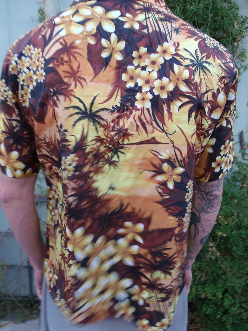May include: A brown and yellow short-sleeved shirt with a tropical print featuring palm trees and flowers.