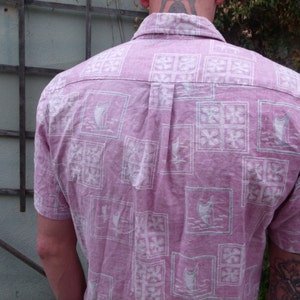May include: A pink button-down shirt with a white floral pattern. The shirt has a short sleeve and a collared neckline.