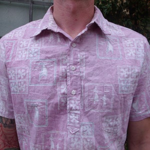 May include: A pink short-sleeved button-down shirt with a white geometric pattern. The shirt has a collar and a button-up front.