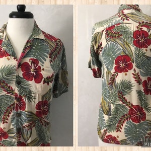 May include: A short-sleeved button-up shirt with a tropical print featuring red hibiscus flowers and green leaves on a cream background.
