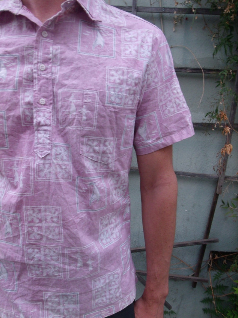 May include: A pink short-sleeved button-down shirt with a white geometric pattern.
