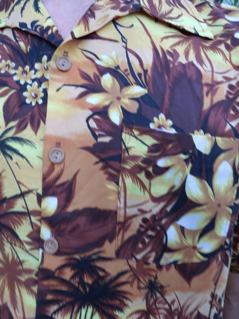 May include: A brown and yellow patterned shirt with a tropical print. The shirt has a button-up collar and a pocket on the left side.