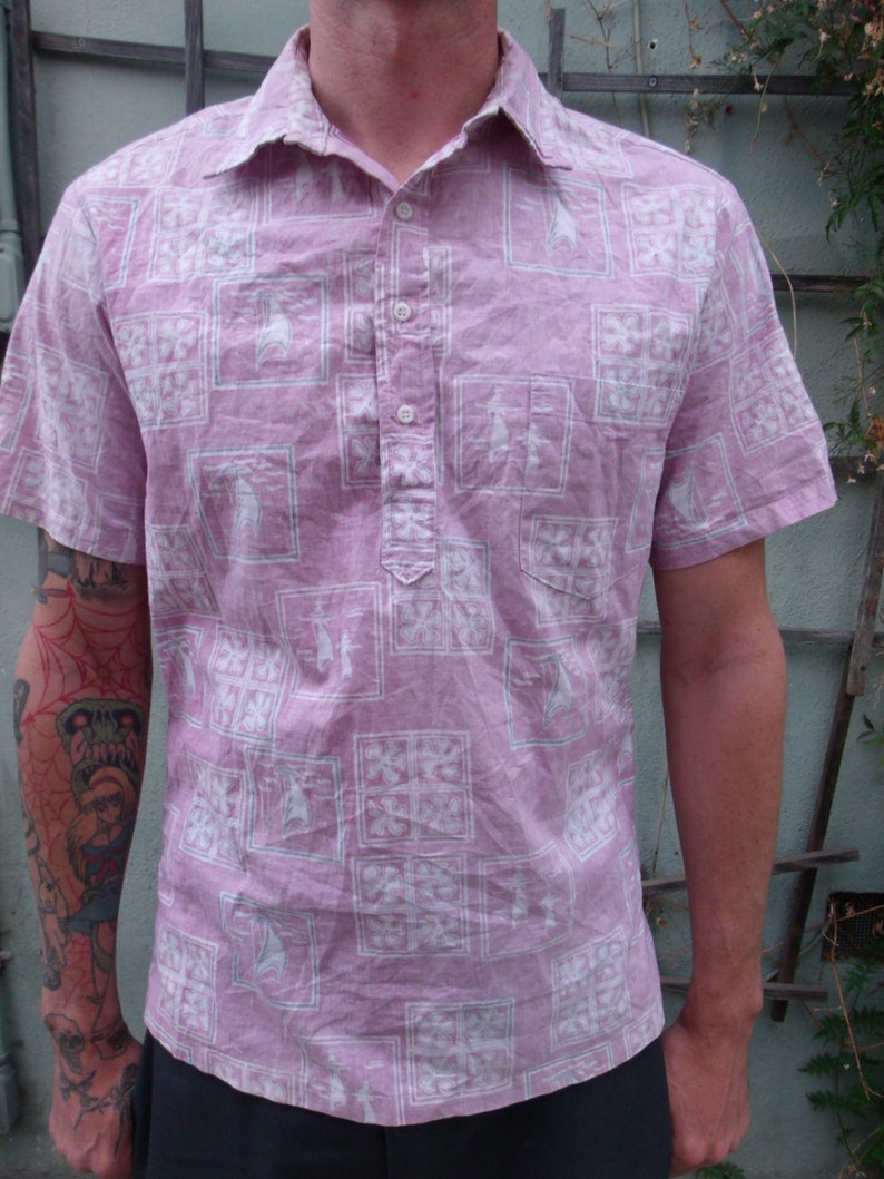 May include: A pink short-sleeved button-down shirt with a white geometric pattern. The shirt has a button-up collar and a button placket.