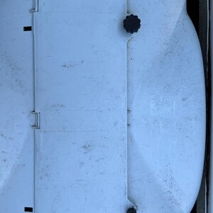 Puede incluir: Un contenedor de almacenamiento de pl&aacute;stico blanco con una tapa con bisagras y dos pomos negros. El contenedor tiene una superficie texturizada y est&aacute; ligeramente sucio.