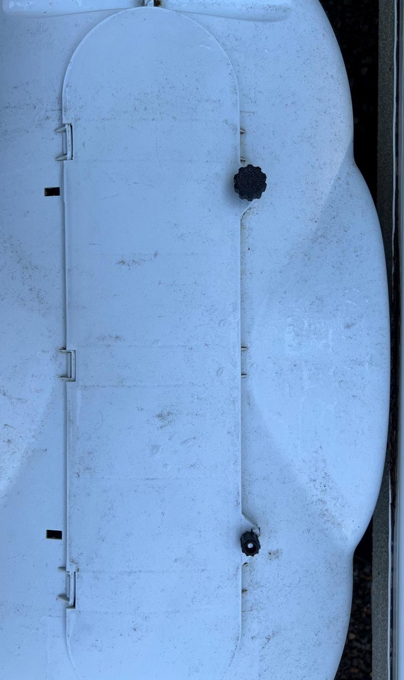 Puede incluir: Un contenedor de almacenamiento de pl&aacute;stico blanco con una tapa con bisagras y dos pomos negros. El contenedor tiene una superficie texturizada y est&aacute; ligeramente sucio.