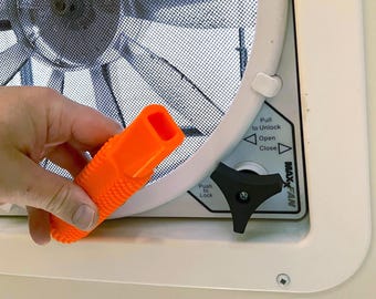 May include: An orange plastic vent window handle with a textured surface. The handle is used to open and close a vent window. The window has a black mesh screen and a white frame. The window also has a black knob with the text "Push to Lock" and a white label with the text "Pull to Unlock, Open, Close" and "Max-Fan".