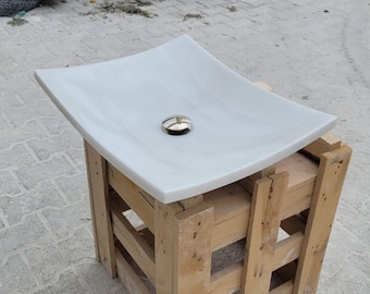 Pode incluir: Pia de banheiro de cerâmica branca com um design curvo, sentada em uma caixa de madeira. A pia tem um único furo de drenagem com uma tampa de drenagem cromada.