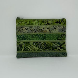 May include: A green fabric zippered pouch with a variety of green patterned fabric strips. The patterns include leaves and other botanical designs. The zipper is green.