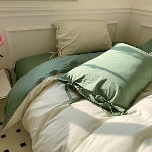 May include: A white and green bedding set with two pillows. The top pillow is white and the bottom pillow is green. The bedding is made of soft, comfortable fabric.
