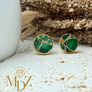 May include: A pair of gold-toned earrings with green and gold stone accents. The stones have a marbled pattern.
