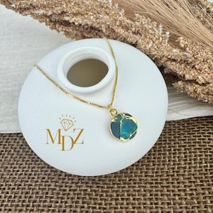 May include: A gold chain necklace with a round pendant featuring a green and blue stone with gold accents.