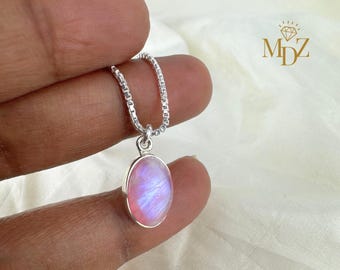 May include: A silver necklace featuring an oval, iridescent, pink and blue pendant. The pendant is set in a silver bezel and hangs from a delicate silver chain. The necklace is shown against a white backdrop.
