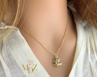 May include: A gold chain necklace with a small, colorful frog pendant. The frog is decorated with sparkling rhinestones.