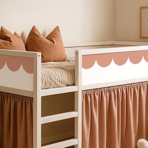 May include: A white bunk bed with a scalloped design in a muted pink color. The bed has a ladder and is adorned with rust-colored pillows and a matching bed skirt. The bedding features a striped pattern.