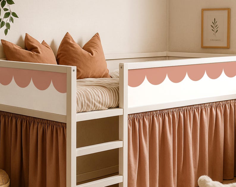May include: A white bunk bed with a scalloped design in a muted pink color. The bed has a ladder and is adorned with rust-colored pillows and a matching bed skirt. The bedding features a striped pattern.