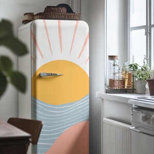 May include: A white refrigerator with a colourful sun and waves design. The design features a yellow sun with pink rays and blue waves.