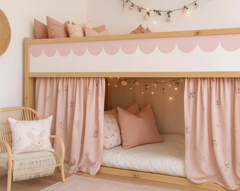 May include: A light wood bunk bed with pink scalloped trim and curtains. The bed is decorated with pink pillows and a floral garland. A wicker chair with a bunny pillow sits in front of the bed.