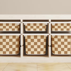 Op de afbeelding: Een wit houten rek met zes bruine en beige geruite opbergbakken. De bakken zijn allemaal even groot en zijn gerangschikt in twee rijen van drie.