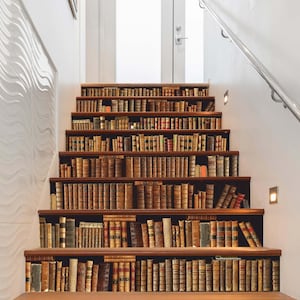 May include: A set of stairs with a bookshelf design. The stairs are painted a light brown colour and the bookshelves are filled with books of various colours and sizes.