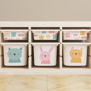May include: A set of six white storage bins with colorful animal designs. The bins are arranged in three rows of two, with each bin featuring a different animal: a bear, a bunny, a fox, a cloud with a rainbow, a sun with a cloud, and a cloud with a rainbow. The bins are all the same size and shape, and they are made of a durable plastic.