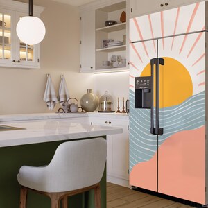 May include: A white refrigerator with a colourful abstract design featuring a sun, waves, and a pink and orange background. The design is reminiscent of a sunset over the ocean.
